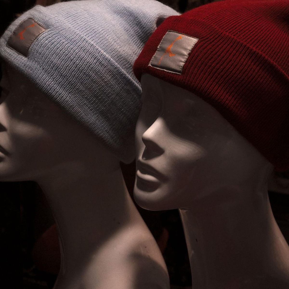 Knit beanies in grey and red shown on mannequin heads