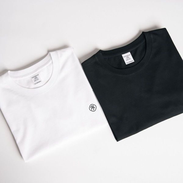 A white and a black crew-neck t-shirt folded side by side on a plain background