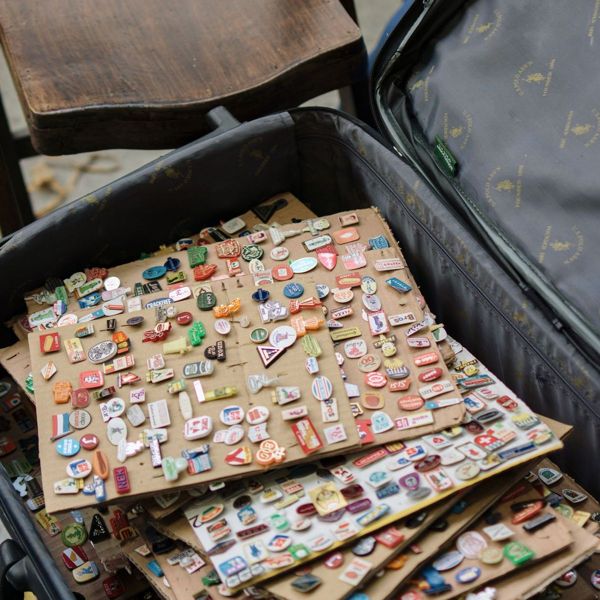 An open suitcase filled with rows of colourful enamel pins
