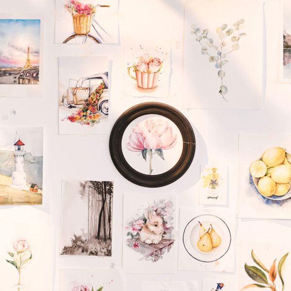 Botanical and landscape art prints arranged on a wall around a round mirror