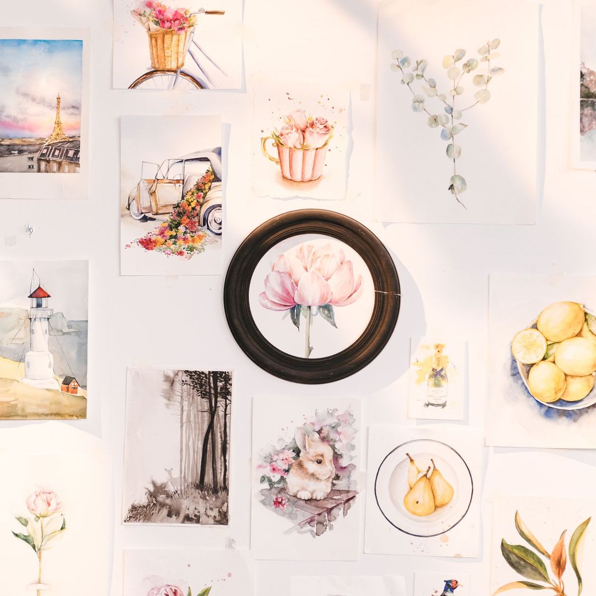 Botanical and landscape art prints arranged on a wall around a round mirror