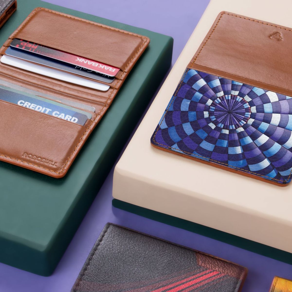 Brown leather card wallets and cardholders laid out on a green and violet surface